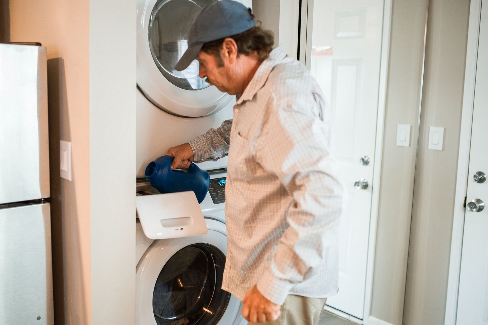 Man adding detergent to a stacked washer and dryer at home